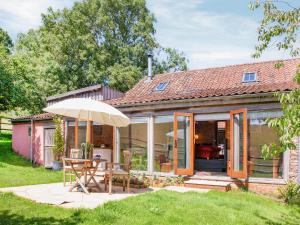 une maison avec une table et un parasol dans l'établissement Parish Land Barn, à Spaxton