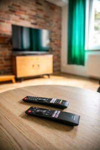 two remote controls sitting on a table in front of a television at Vistula River Modern Apartment in Krakow