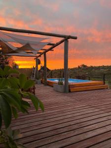a wooden deck with a swimming pool at sunset at DARMI in Villa Serrana