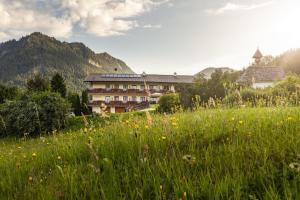 ein Grasfeld mit einem Gebäude im Hintergrund in der Unterkunft Gästehaus Heißenlehen in Ramsau bei Berchtesgaden