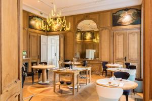 a restaurant with tables and chairs and a chandelier at Clarance Hotel Lille in Lille