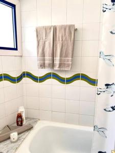 a white bathroom with a tub and a towel at Stunning sunset ocean view apt. in Taurito