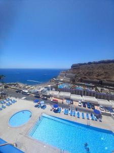 an aerial view of a resort with two pools and chairs at Stunning sunset ocean view apt. in Taurito