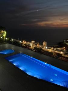 a blue swimming pool on the roof of a building at night at Stunning sunset ocean view apt. in Taurito