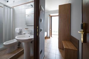 uma casa de banho branca com um lavatório e um WC em Roof Garden Rooms em Assis