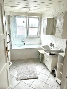 un bagno bianco con vasca e lavandino di Rosi's Ferienwohnung im Haus Sieglinde a Prien am Chiemsee