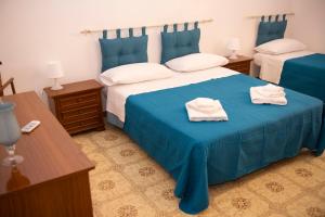um quarto com 2 camas com lençóis azuis e almofadas brancas em Casa vacanza “La Maison de famille” em Surbo