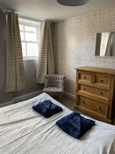 a bedroom with a bed and a dresser and a window at The flat at the crooked house in Ulverston