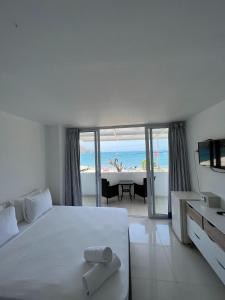 Schlafzimmer mit einem weißen Bett und Strandblick in der Unterkunft La Ballena Azul Hotel in Taganga