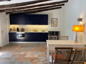 een keuken met blauwe kasten en een tafel met stoelen bij Charming cottage, pool & garden by Guincho beach in Aldeia de Juso
