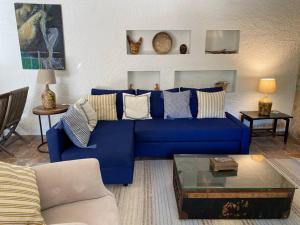 een blauwe bank in een woonkamer met een tafel bij Charming cottage, pool & garden by Guincho beach in Aldeia de Juso
