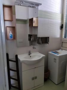un baño blanco con lavabo y lavadora y secadora. en Come a Casa - Like home en Tocco da Casauria