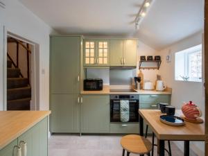 a kitchen with green cabinets and a wooden table at Meadowland in Thornham Magna