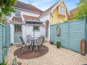 un patio con mesa, sillas y una valla en Meadowland en Thornham Magna