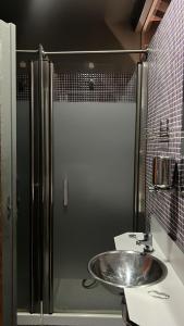 uma casa de banho com um lavatório e um chuveiro em Albergue & Cafetería Vía de la Plata Hervás em Hervás