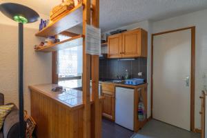 Appartement Prarion Mont Blanc في لي أوش: مطبخ صغير مع دواليب خشبية وثلاجة بيضاء