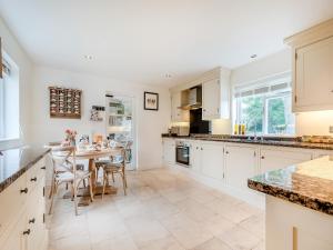 a kitchen with white cabinets and a table and chairs at The Cottage At West Brinsea Farm in Churchill