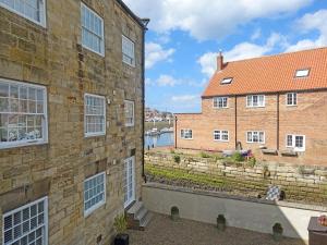 two brick buildings with a view of a river at Sail Loft Apartment in Whitby