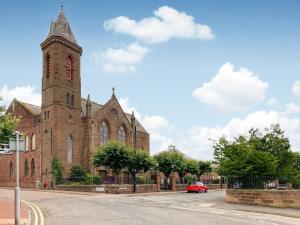 a red car parked in front of a church with a tower at Apartment One - Uk44284 in Arbroath