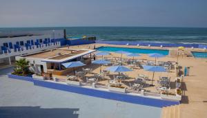 een uitzicht over een zwembad met parasols en de oceaan bij hotel tropicana in Casablanca