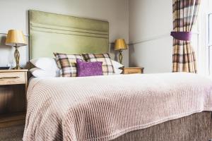 a bedroom with a large bed with purple pillows at Cove Bay Hotel in Aberdeen