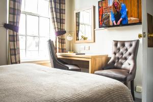 um quarto de hotel com uma cama e duas cadeiras e uma secretária em Cove Bay Hotel em Aberdeen