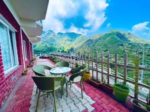 a patio with tables and chairs on a balcony with mountains at Kempty Myst Resort, Mussoorie - A Comfortable Stay in Mussoorie