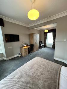 um quarto de hotel com uma cama, uma secretária e uma televisão em Cove Bay Hotel em Aberdeen