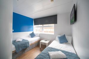 2 łóżka w małym pokoju z niebieskimi ścianami w obiekcie CiTi Hotel London Luton w Luton