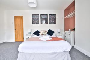 a white bedroom with a large white bed and two tables at Bradely st in Cardiff