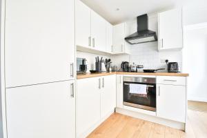 a white kitchen with white cabinets and a stove at Bradely st in Cardiff