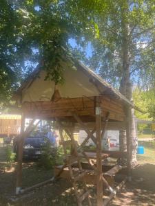 a tree house with a thatched roof under a tree at Le bivouac-tente chez Camille in Veynes