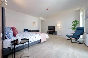 a bedroom with a bed and two chairs and a television at Siena Hills Apartments in Siena
