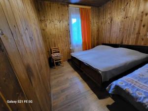 una camera da letto con pareti in legno, un letto e una sedia di Peak House a Kazbegi