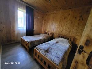 2 letti in una camera con pareti in legno di Peak House a Kazbegi