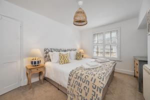 a white bedroom with a bed and a window at The Limes - Beautiful Townhouse in Oakham in Oakham