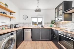 a kitchen with black cabinets and a washer and dryer at The Limes - Beautiful Townhouse in Oakham in Oakham