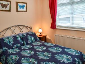 a bedroom with a bed with a blue comforter and a window at River Breeze in Horning