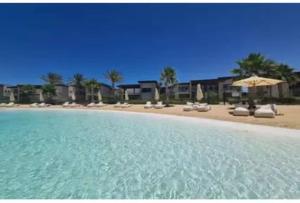 a view of a beach with chairs and umbrellas at Swanlake North Coast Luxury Villa in Zāwiyat al ‘Awwāmah
