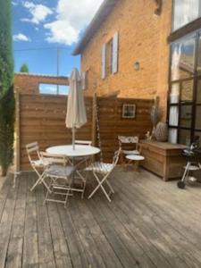 a patio with a table and chairs and an umbrella at La maison de Fanny in Jarnioux +14 photos
