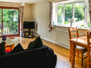 sala de estar con sofá, mesa y ventanas en Woodside Fishery - The Plover en Cleobury Mortimer