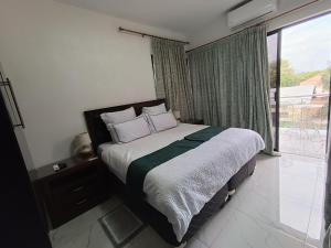 a bedroom with a bed and a large window at Manasseh Guesthouse in Gaborone