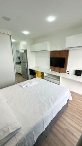 een groot wit bed in een kamer met een keuken bij Moov 2517 Studio Mooca in Sao Paulo