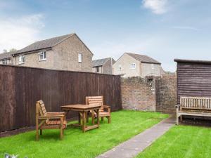 un patio trasero con una mesa y sillas y una valla en Woodlander en Dorchester