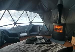 Una habitación con cama y chimenea en una tienda de campaña en Arctic Nature Experience Glamping en Vuontisjärvi