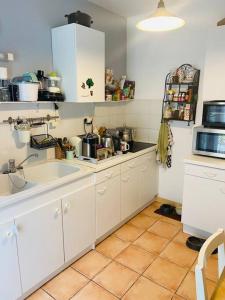 een keuken met witte kasten en een tegelvloer bij Charmante maison douillette de 65 m2 pour 4 pers. in Saint-Pierre-dʼOléron