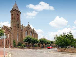 um carro vermelho estacionado em frente a uma igreja com uma torre em Apartment Four - Uk44287 em Arbroath