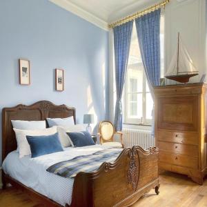um quarto com uma cama com paredes azuis e uma janela em The Stay Well em Boulogne-sur-Mer
