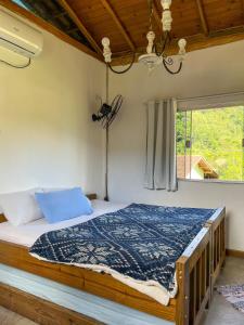 1 dormitorio con 1 cama con edredón azul y ventana en Flat aconchegante próximo à Trindade e Paraty, en Paraty