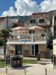 un edificio con mesas y sombrillas delante en Dalmatian Villa Denis, en Bol